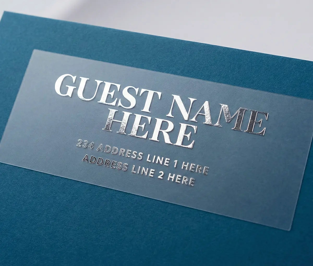 Custom Guest address sticker featuring bold statement serif font printed in silver foil on transparent matte vinyl and applied to a blue envelope.