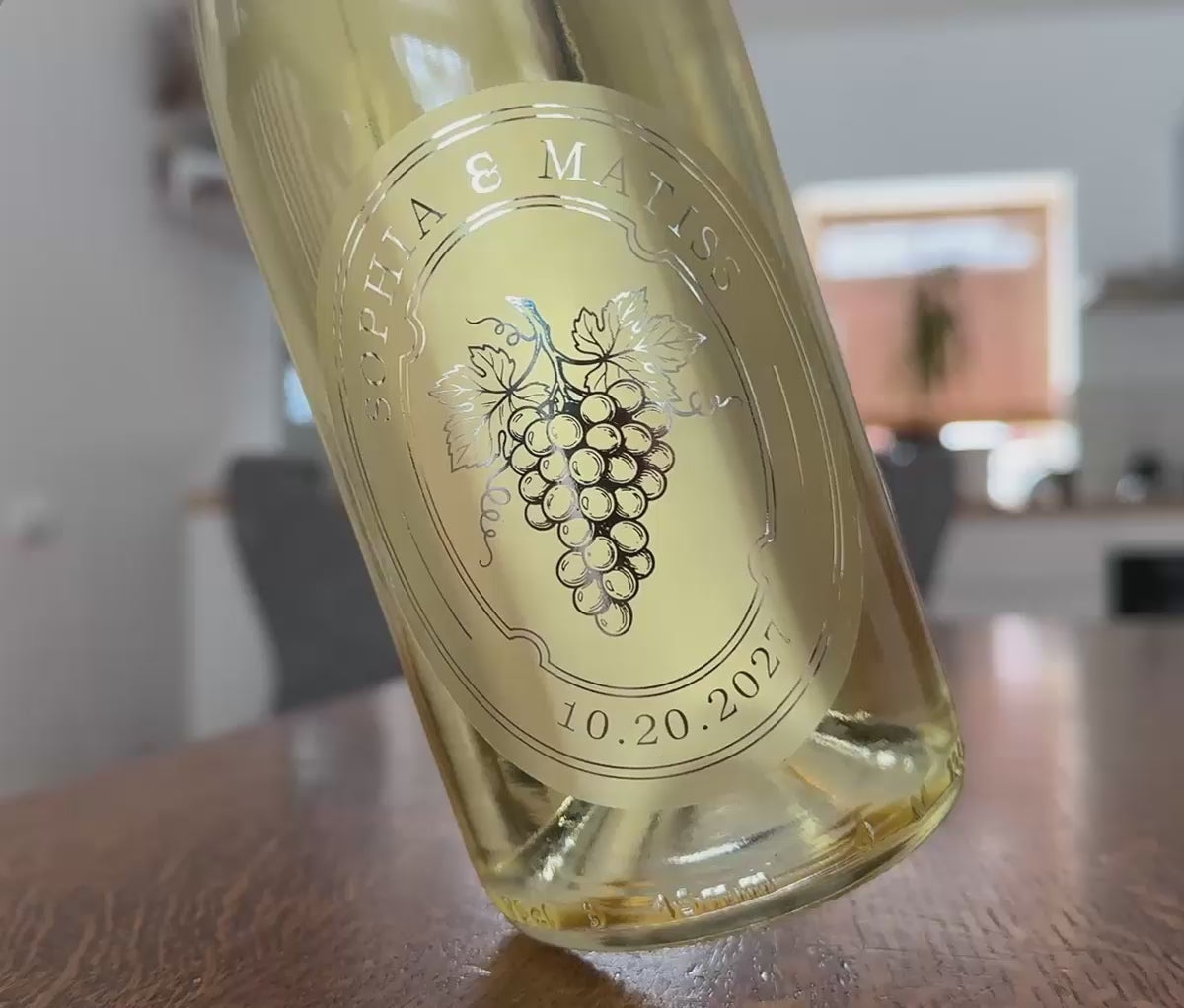 Personalized frosted wedding favour sticker applied to a white wine bottle. Bottle is being rotted slightly to show the shine of the silver foil print.