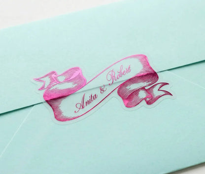 Light Blue envelope with ribbon-shaped wedding envelope sticker printed in Hot Pink foil and custom names.