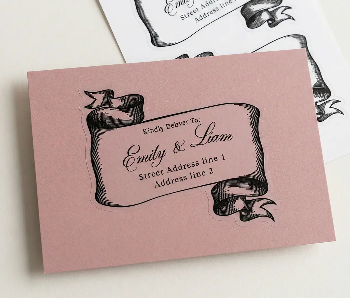 Black ribbon design return address label on pink envelope.