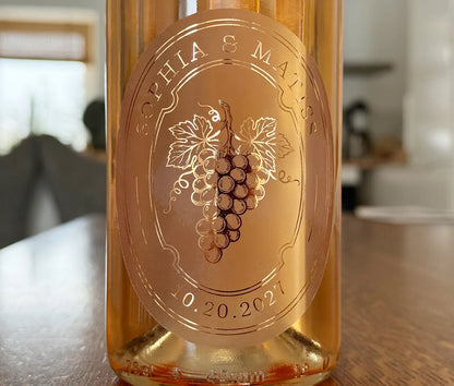 Rose wine bottle with an oval personalized frosted label featuring grapes printed in rose gold foil.