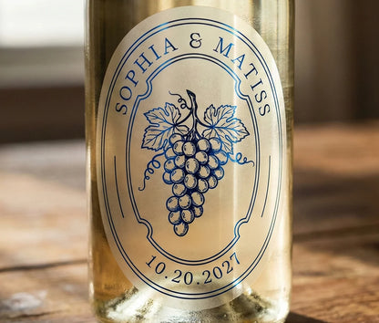 White wine bottle with an oval personalized frosted label featuring grapes printed in royal blue foil.